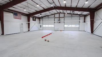 A large indoor space with a high ceiling, a volleyball net, and a row of red and white balls.