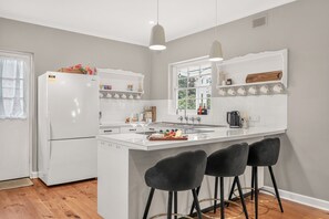 A modern kitchen with a central island, bar stools, and a window with a view.