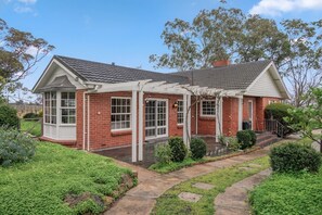 A brick house with a covered porch and a garden pathway.