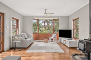 A spacious living room with a large window, a sofa, a television, and a fireplace.