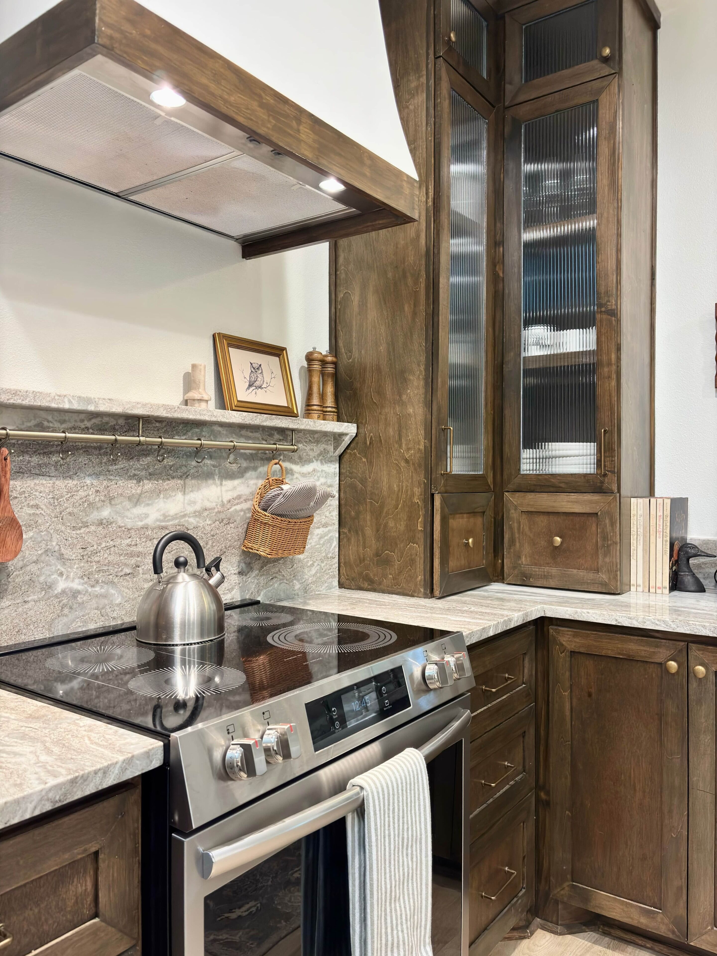 A kitchen with a stainless steel stove, wooden cabinets, a marble countertop, and a built-in oven.