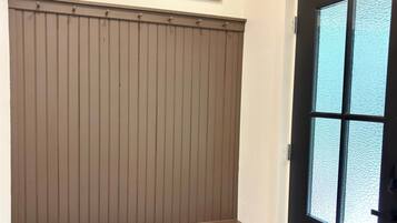 Une pièce avec un banc en bois, deux tableaux encadrés au mur et une porte dont les panneaux sont en verre dépoli.
