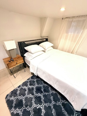 Una camera da letto con un letto, un comodino, una lampada e un tappeto decorato.