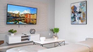 Un salon moderne avec un téléviseur à écran plat fixé à un mur texturé, un meuble de rangement blanc, une table basse et un canapé.