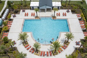 A large rectangular pool with a surrounding deck area, equipped with multiple lounge chairs and a covered seating area. - 2BD Prime Location & Free Resort Access! (Kissimmee)