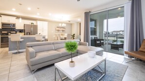 Un salon moderne avec un canapé, une table basse et une vue sur la ville grâce à de grandes fenêtres.