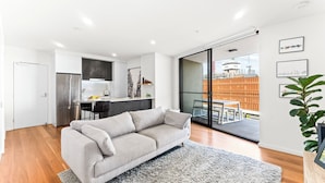 Ein modernes Apartment mit Küche, Essbereich und Wohnzimmer mit Sofa und großem Fenster.