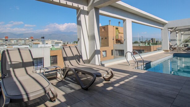 Uma área de piscina no terraço com espreguiçadeiras e vista desobstruída da paisagem urbana.