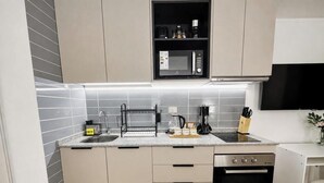 Uma cozinha moderna com micro-ondas embutido, cafeteira e máquina de lavar loiça.