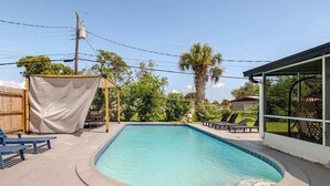 A rectangular swimming pool with a shaded area and lounge chairs. - Spacious Cocoa Retreat Near Beach & Port (Cocoa)