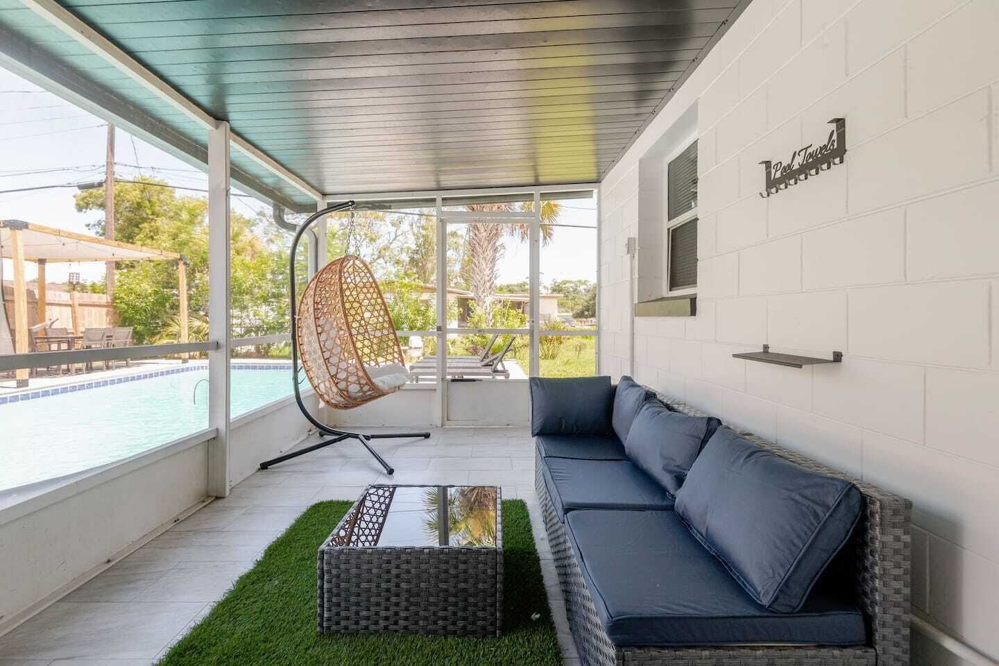 A modern outdoor seating area with a pool view, a hanging chair, and a sofa.