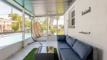 A modern outdoor seating area with a pool view, a hanging chair, and a sofa.