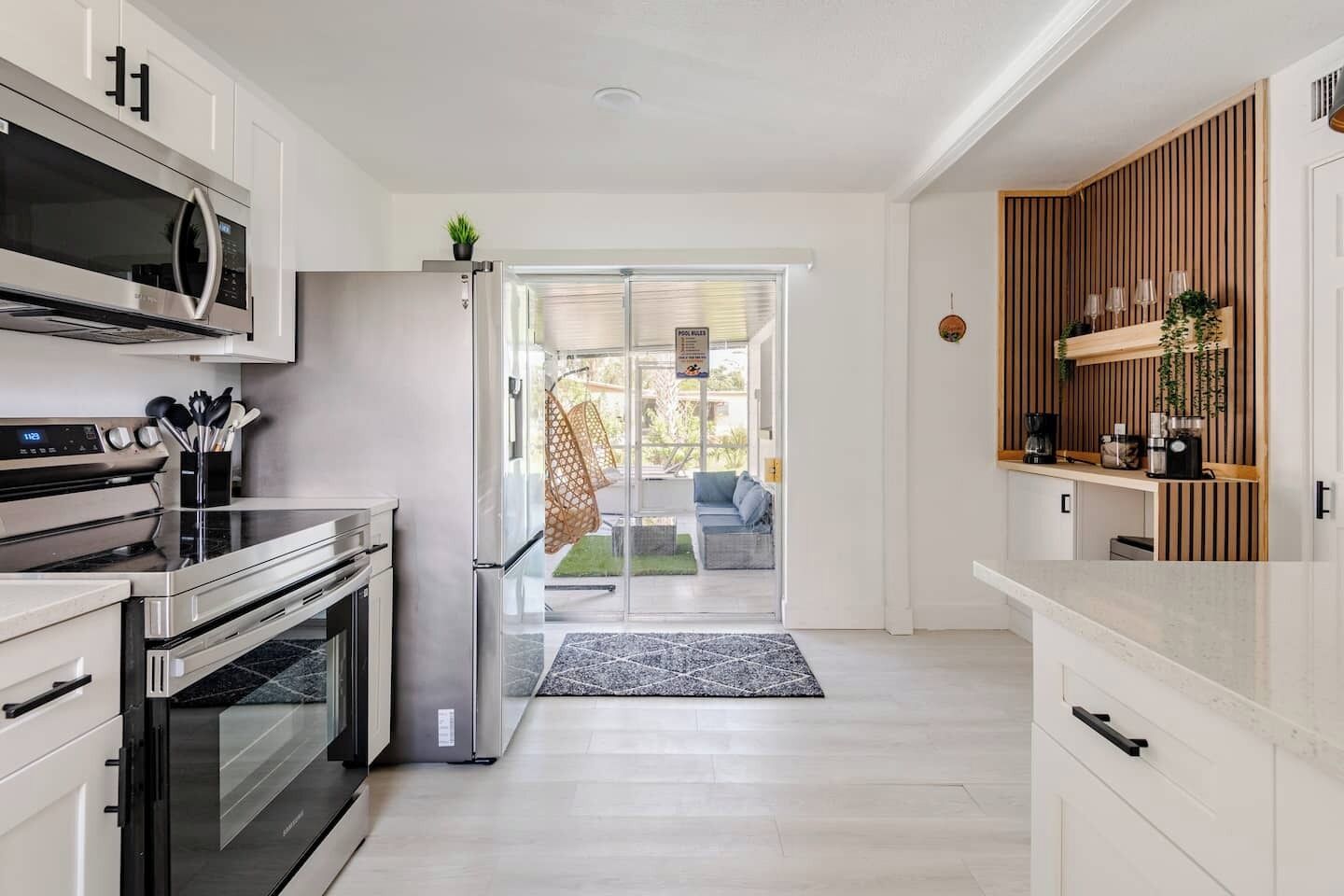 Une cuisine moderne dotée d’appareils électroménagers en acier inoxydable, d’un mur d’accent en bois et donnant sur un espace de vie.