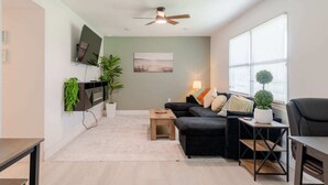 A modern living room with a sofa, coffee table, and a TV mounted on the wall. - Spacious Cocoa Retreat Near Beach & Port (Cocoa)