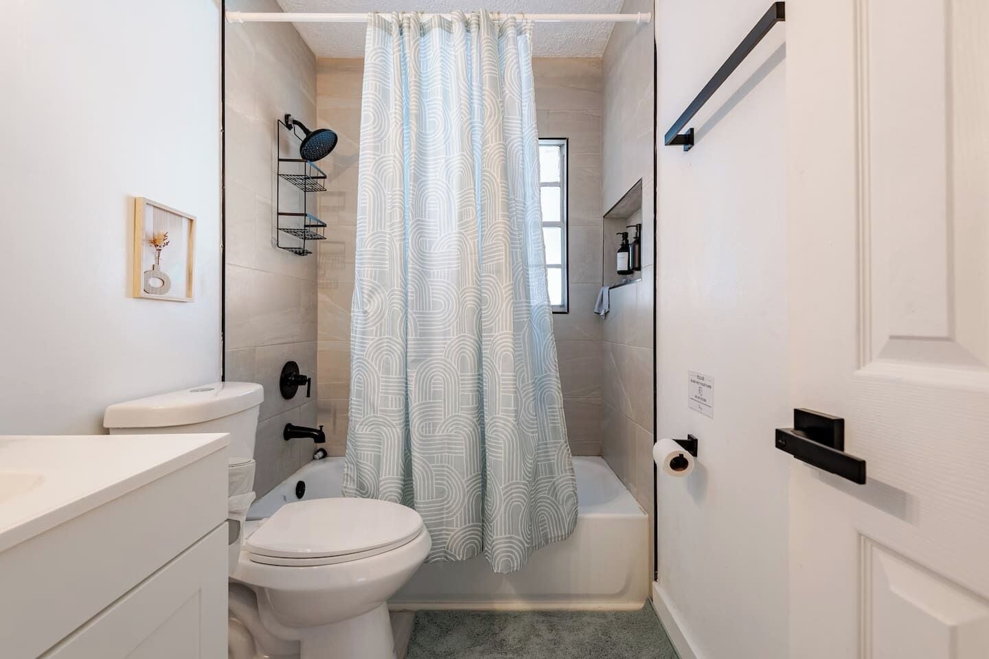 Un baño con inodoro, lavamanos, ducha y toallero.