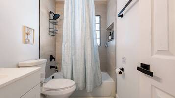 Un baño con inodoro, lavamanos, ducha y toallero.