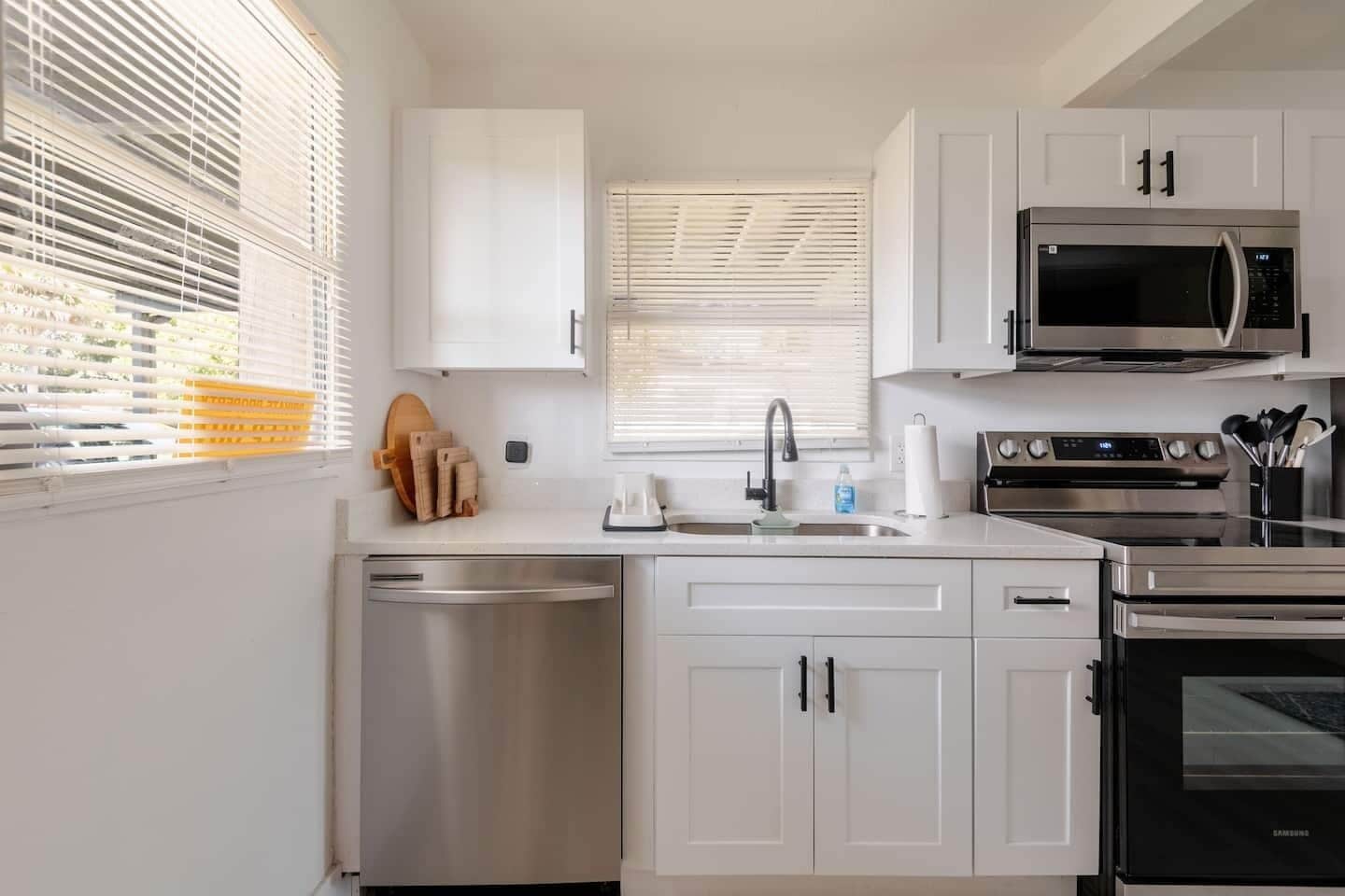 A modern kitchen with white cabinets, stainless steel appliances, and a dishwasher.