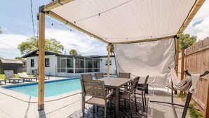 A backyard with a pool, a covered patio area with a table and chairs, and a hammock. - Spacious Cocoa Retreat Near Beach & Port (Cocoa)
