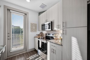 Eine kleine Küche mit eingebautem Backofen, Mikrowelle und Kühlschrank.