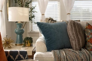 Ein gemütliches Wohnzimmer mit einer Couch, einer Lampe und dekorativen Kissen.