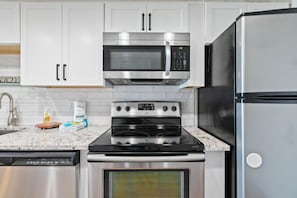 Eine moderne Küche mit Edelstahlgeräten, darunter eine Mikrowelle, ein Backofen und ein Kühlschrank.