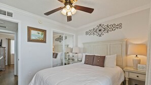 A bedroom with a bed, bedside table, lamp, ceiling fan, and a mirror. - Stunning 2 BR Condo - Bring your Boat to the Beach - GSSR 709A (Gulf Shores)