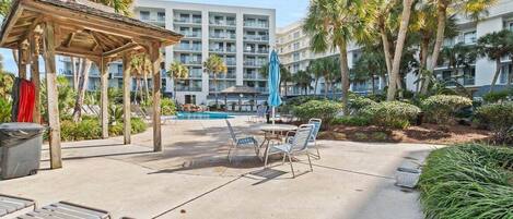 A hotel courtyard with a pool, lounge chairs, and a gazebo.