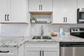 A modern kitchen with white cabinetry, a stainless steel sink, and a built-in microwave. - Stunning 2 BR Condo - Bring your Boat to the Beach - GSSR 709A (Gulf Shores)
