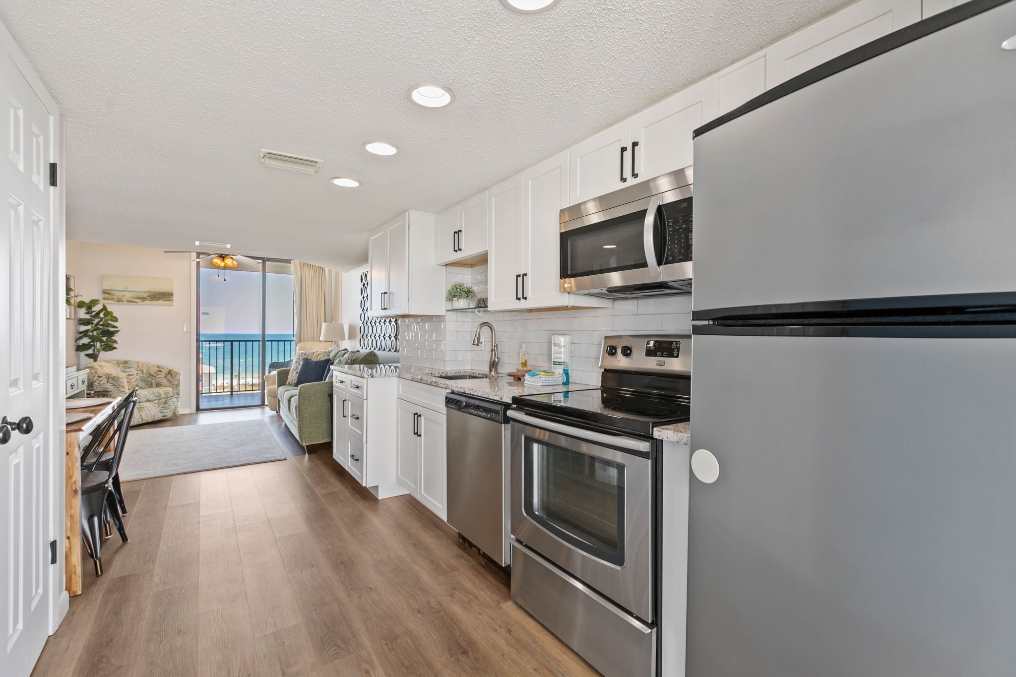 A modern kitchen with stainless steel appliances, white cabinetry, and a view to the outside.