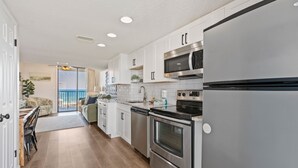 A modern kitchen with stainless steel appliances, white cabinetry, and a view to the outside. - Stunning 2 BR Condo - Bring your Boat to the Beach - GSSR 709A (Gulf Shores)