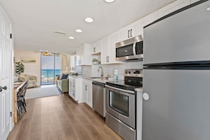 A modern kitchen with stainless steel appliances, white cabinetry, and a view to the outside. - Stunning 2 BR Condo - Bring your Boat to the Beach - GSSR 709A (Gulf Shores)