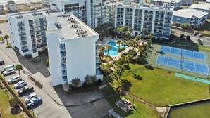 A coastal hotel complex with multiple buildings, a swimming pool, tennis courts, and a parking area. - Stunning 2 BR Condo - Bring your Boat to the Beach - GSSR 709A (Gulf Shores)