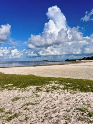 A beach with a clear sky and clouds, a sandy shore, and a calm sea. - Private Pool • Game Room • Fire Pit • Boat Parking (Crystal River)