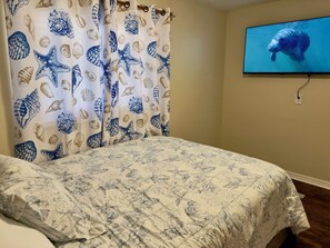 A bedroom with a bed, a television on the wall, and a curtain with a seashell pattern. - Private Pool • Game Room • Fire Pit • Boat Parking (Crystal River)
