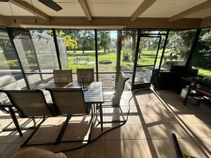 A sunlit patio with a table and chairs, a grill, and a view of a landscaped garden. - Private Pool • Game Room • Fire Pit • Boat Parking (Crystal River)