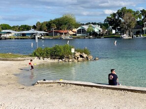 A waterfront area with a sandy beach, a dock with boats, and houses in the background. - Private Pool • Game Room • Fire Pit • Boat Parking (Crystal River)