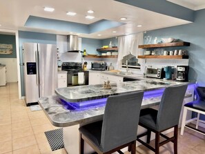 A modern kitchen with a central island, built-in appliances, and a breakfast bar. - Private Pool • Game Room • Fire Pit • Boat Parking (Crystal River)