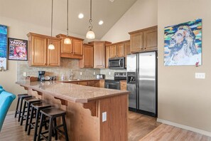 A kitchen with wooden cabinets, stainless steel appliances, and a central island with bar stools. - Club Yakov & 3BDR Lakefront (Hollister)