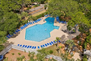 An aerial view of a swimming pool surrounded by blue lounge chairs, with a wooden deck and a small building with a solar panel. - Bluff Villa in Sea Pines Near South Beach Marina, Tennis, Pickleball & Golf (Hilton Head Island)