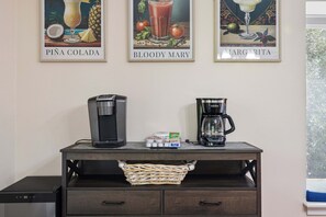 Un coin café équipé de deux machines à café, d’un panier de sachets de thé et d’un menu encadré accroché au mur.