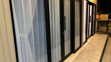 A row of hotel rooms with sliding glass doors and a tiled floor.