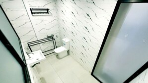 A bathroom with a toilet, sink, and shower area. - Umah Delod Dangin (Ubud)