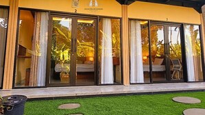 A guest house with large sliding glass doors, a balcony, and a well-maintained lawn. - Umah Delod Dangin (Ubud)