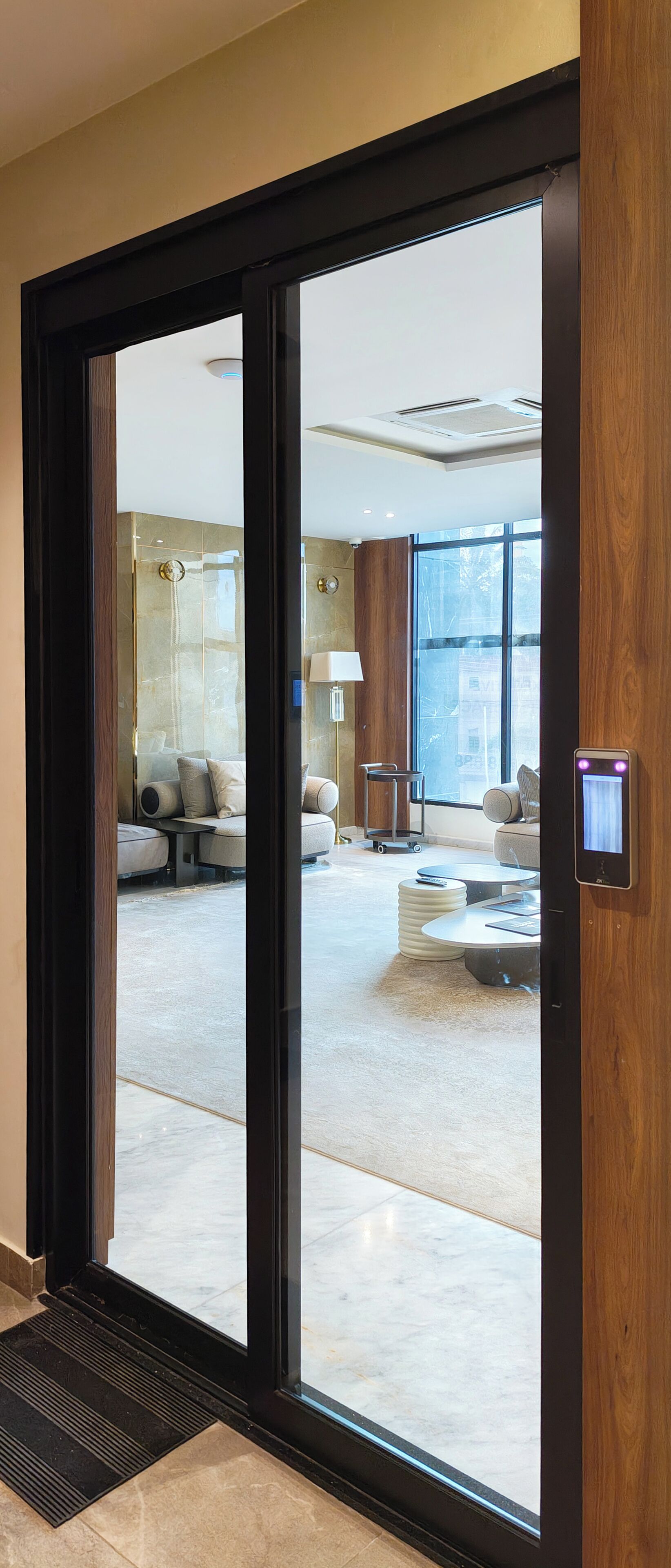 A modern interior with a sliding glass door leading to a living area with a sofa, coffee table, and a lamp.