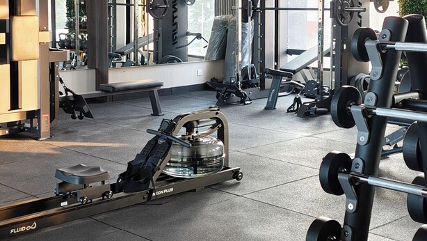 Ein Fitnessstudio mit verschiedenen Trainingsgeräten, darunter Kraftmaschinen und Kurzhanteln.