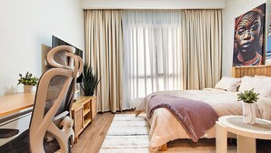 Ein Hotelzimmer mit einem Bett, einem Schreibtisch, einem Sessel, einem Fernseher und einem Bild an der Wand.