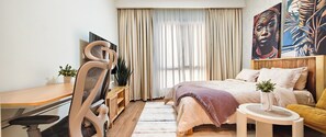 Ein Hotelzimmer mit einem Bett, einem Schreibtisch, einem Sessel, einem Fernseher und einem Bild an der Wand.