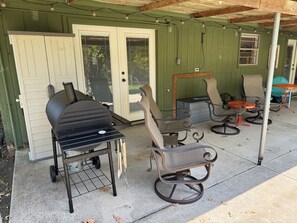 A patio with a grill, outdoor chairs, and a table.