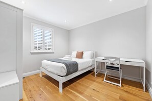A bedroom with a bed, a desk, and a window with blinds. - Spacious Parnell Home at Auckland Domain by Zodiak (Auckland City)