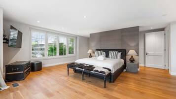 A bedroom with a bed, bedside lamps, a suitcase, and a window with blinds.